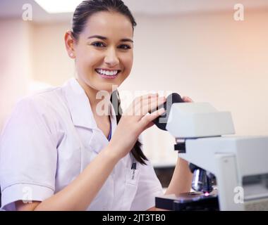 The answers are right under this microscope. Portrait of a young scientist using a microscope in a laboratory. Stock Photo