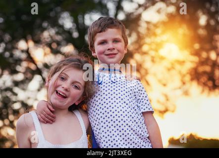 Being a big brother is better than being a superhero. a little boy and his sister standing outside. Stock Photo