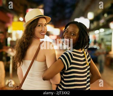 Breaking away with my bestie. Portrait of two happy young friends exploring a foreign city at night. Stock Photo