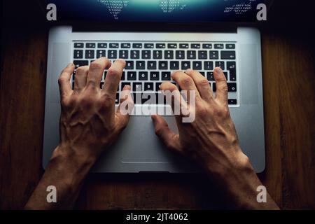 Programming like theres no tomorrow. High angle shot of an unidentifiable man using a laptop late at night. Stock Photo
