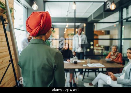 Team leader giving a speech during a boardroom meeting. Muslim businesswoman sharing her creative strategy with her colleagues. businesswoman wearing Stock Photo
