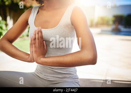 Keeping to her yoga routine. a sporty young woman practicing yoga outdoors. Stock Photo