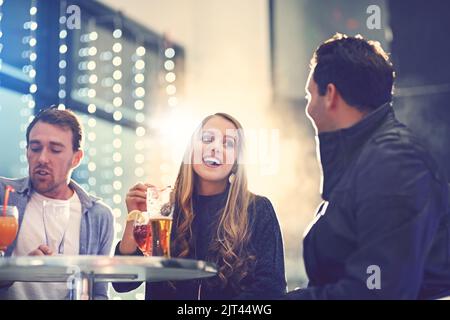 Strike up a conversation. a group of friends relaxing with cocktails in a nightclub. Stock Photo