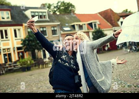 Taking crazy selfies. a young couple taking selfies while on vacation. Stock Photo