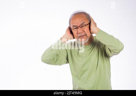 Deaf. Portrait senior old man with glasses sad covering ears with fingers hands studio shot isolated on yellow background, Asian unhappy elder man Suf Stock Photo