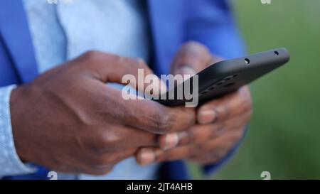Black man in blue blazer enters information into phone Stock Photo