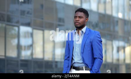 African American man in blue blazer walks past building Stock Photo