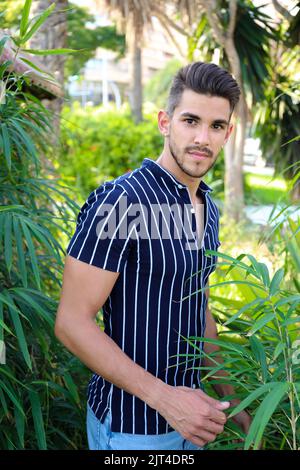 A portrait of dark-haired attractive Spanish man posing in the garden Stock Photo
