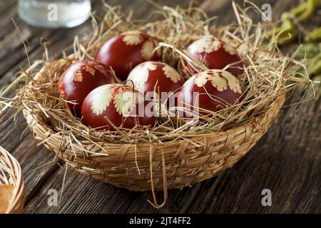Easter eggs colored with onion peels in a wicker basket on a rustic table Stock Photo