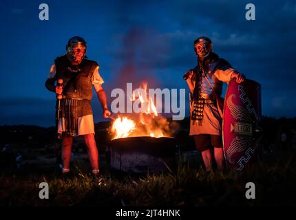 Martin Stiles (left) a member of Roman living history group Secunda Augusta and Douglas Eckhart (right) from the Antonine Guard, stand next to a fire during the reenactment of a night attack at Chesters Roman Fort at Hadrian's Wall in Hexham. Picture date: Saturday August 27, 2022. Stock Photo