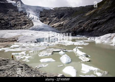 Hiker looking at the schlatenkees glacier, glacier lake and glacier moraine in Venediger mountain group, East Tyrol, Austria Stock Photo