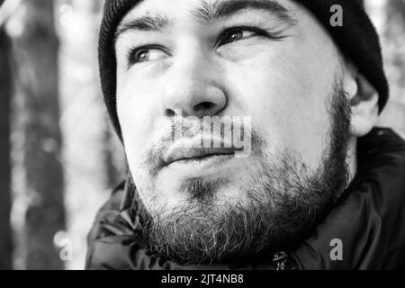 Face of a young man with beard and moustache close-up. Black and white. Selective focus. Outdoors Stock Photo