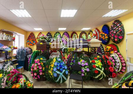 Interior of room with funeral accessories. Shop selling coffins, funeral wreaths and flowers. Stock Photo