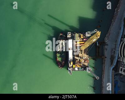 Floating crane dredging barges working on the construction of a marina. Aerial top view Stock Photo