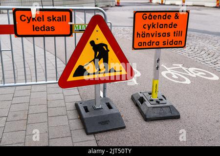 Halmstad, Sweden - August 20, 2022: Road works sign on city street and information board in Swedish language that directs cyclist to the other side of Stock Photo