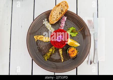 delicious tartare from beef with egg on ceramic plate. Stock Photo