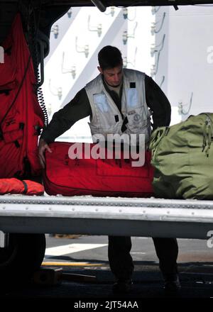 U.S. Naval Aircrewman 2nd Class loads rescue equipment into an MH-60S Knighthawk helicopter attached to Helicopter Sea Combat Squadron (HSC) 23 in preparation for flight operations aboard 101117 Stock Photo