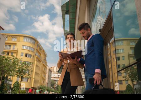 Young talented business couple are working outside in the city on their business project, on a sunny day Stock Photo