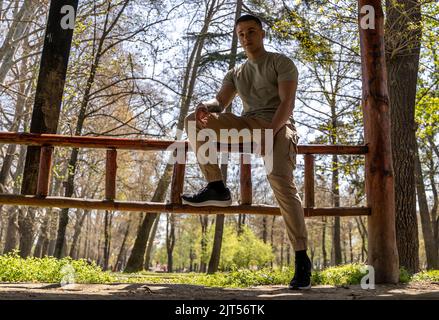 Image of a young strong happy cheery sports man posing outdoors in nature green park looking camera Stock Photo
