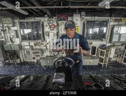 U.S. Navy Seaman steers the ship while standing helmsman watch aboard the guided missile destroyer USS Donald Cook (DDG 75) March 31, 2014, in the Mediterranean Sea 140331 Stock Photo