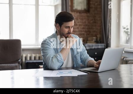 Pensive thoughtful business marketing professional man using laptop computer Stock Photo