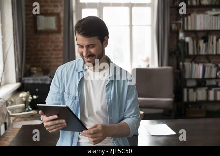 Happy millennial tablet user man reading text on gadget screen Stock Photo