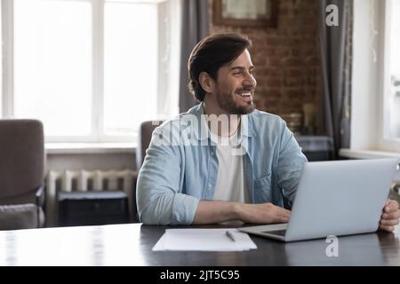Happy freelance businessman smiling, looking away at home office workplace Stock Photo
