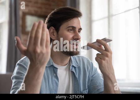 Positive millennial cellphone user man talking on speaker on cellphone Stock Photo