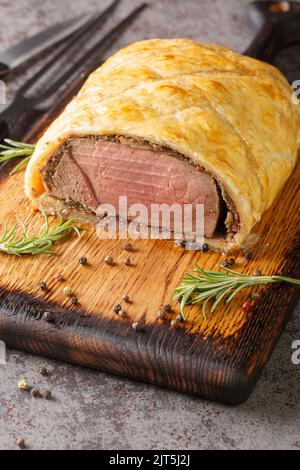Homemade Christmas Beef Wellington with a Pastry Crust closeup on rustic wooden board on the table. Vertical Stock Photo