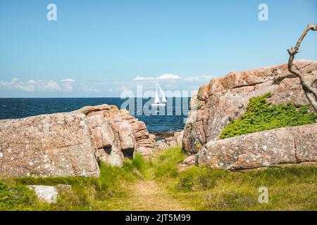 sailboat and rocky coastline of Bornholm in baltic sea, Denmark Stock Photo