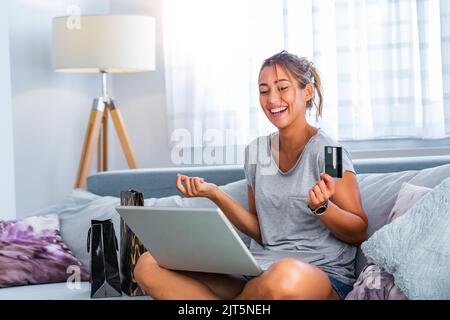 Young woman holding credit card and using laptop computer. Online shopping concept. Happy woman doing online shopping at home Stock Photo