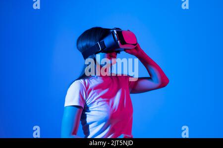 Brunette woman exploring or playing in virtual augmented reality with vr goggles headset in the Metaverse. Stock Photo