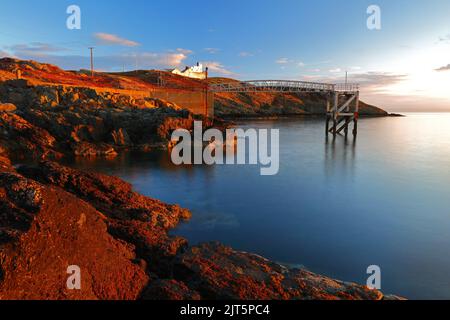 Point Lynas Lighthouse at first light with calm blue sea. Anglesey, North Wales, UK. Stock Photo