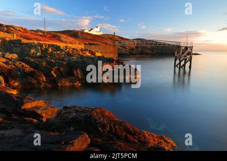 Point Lynas Lighthouse at first light with calm blue sea. Anglesey, North Wales, UK. Stock Photo