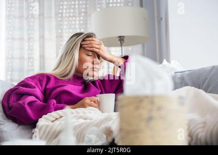 Sick desperate woman has flu. Rhinitis, cold, sickness, allergy concept. Pretty sick woman has runnning nose, rubs nose with handkerchief. Sneezing fe Stock Photo