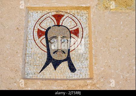 Image of a religious saint in a wall inside of the medieval military fort. The piece of art is made of little square stones with different colors. Stock Photo