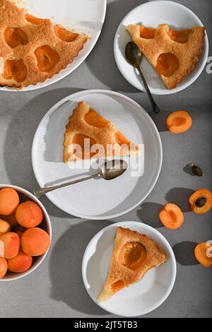 Slices of fresh apricot pie cake with fruits on grey table background. Top view Stock Photo