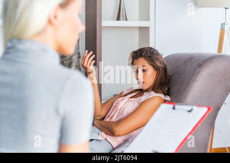 Woman at therapy session. Attentive psychologist. Attentive psychologist holding pencil in her hands making written notes while listening Stock Photo