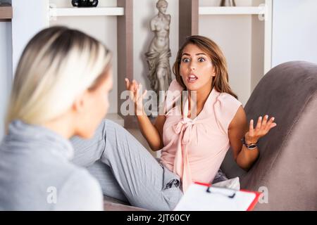 Woman at therapy session. Attentive psychologist. Attentive psychologist holding pencil in her hands making written notes while listening to her clien Stock Photo