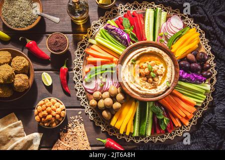 Arabic Cuisine;  Middle Eastern Hummus platter with assorted snacks. Hummus dip with fresh vegetables sticks, falafel, chickpeas and pita bread. Stock Photo