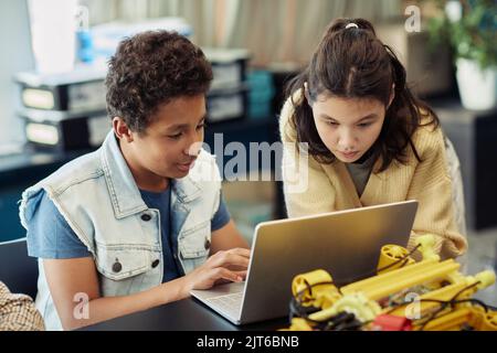 Portrait of boy and girl using laptop together and programming robots during engineering class at school Stock Photo