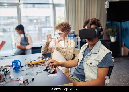 Portrait of two children building robots in engineering class and using VR technology Stock Photo