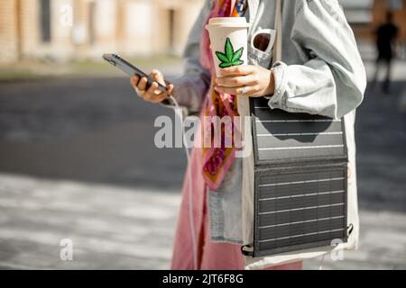 Woman charge phone from portable solar panel while walking outdoors Stock Photo
