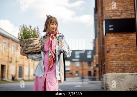 Woman charge phone from portable solar panel while walking outdoors Stock Photo