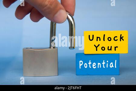 Unlock your potential text wooden blocks with hand holding padlock. Motivational concept. Stock Photo