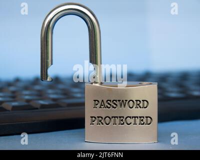 Password protected text engraved on padlock with blurred keyboard background. Password security concept. Stock Photo