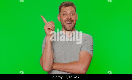 Eureka. Inspired man pointing finger up with open mouth, having good idea, plan, startup, showing inspiration motivation gesture, problem solution. Adult guy on green chroma key studio background Stock Photo
