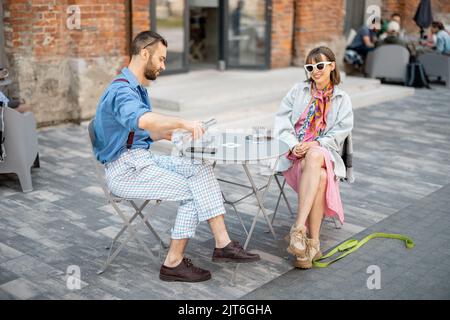 Stylish couple of colleagues have a conversation while sitting at cafe terrace Stock Photo