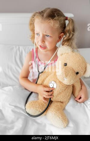 The child treats the bear. Play during illness. Stock Photo