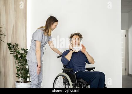 Medical worker communicates with a man in a wheelchair with neck injury Stock Photo